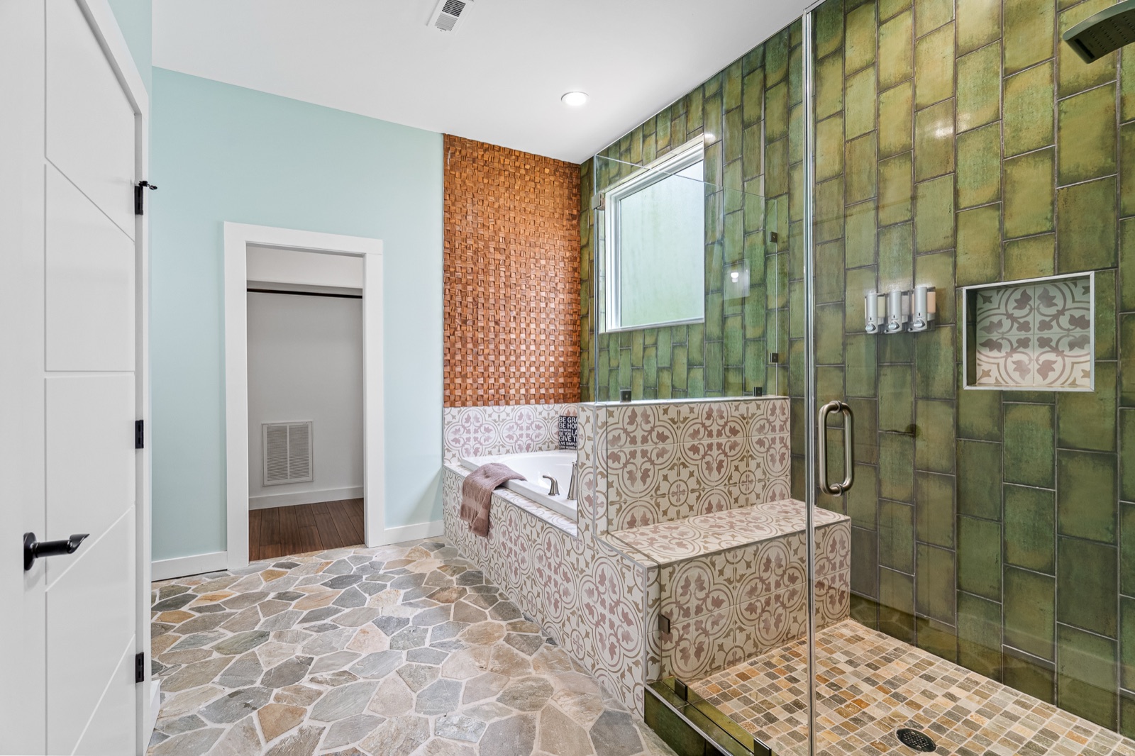 Renovated bathroom with emerald green tile walk-in shower, patterned tile tub surround, and natural stone flagstone flooring