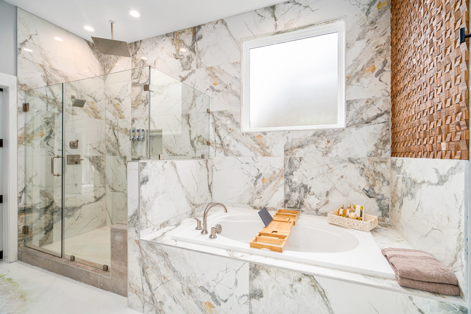 Luxury bathroom with soaking tub, glass shower, and copper textured accent wall