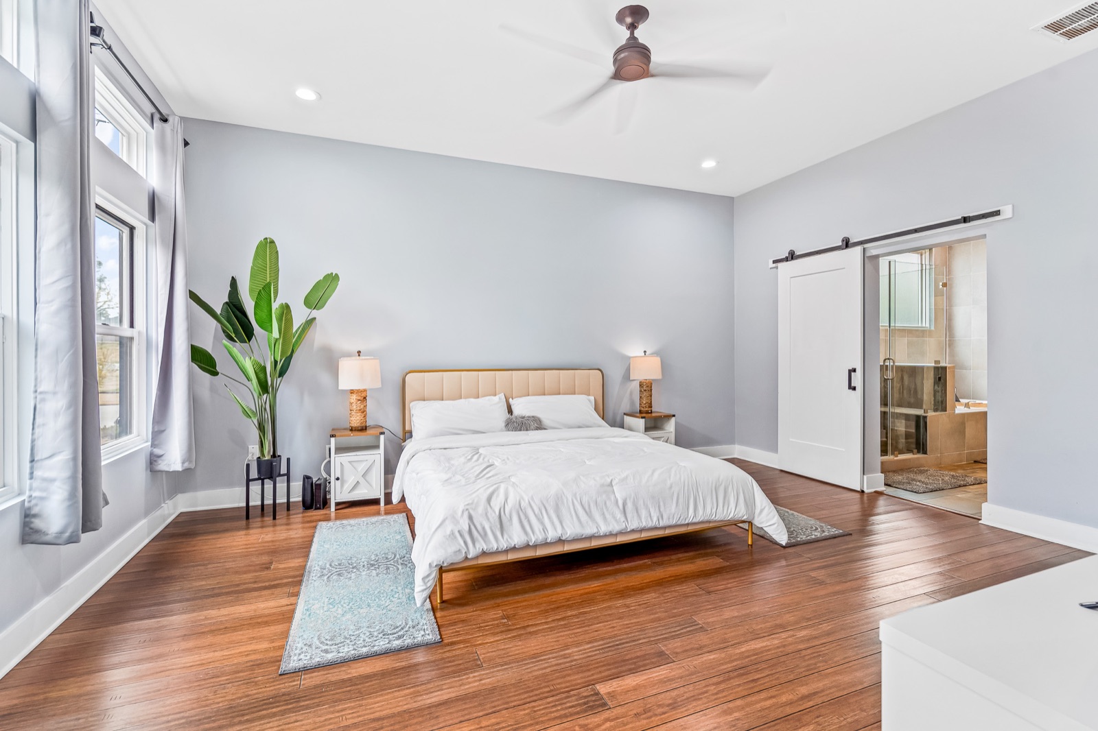 Spacious primary bedroom with upholstered bed and sliding barn door