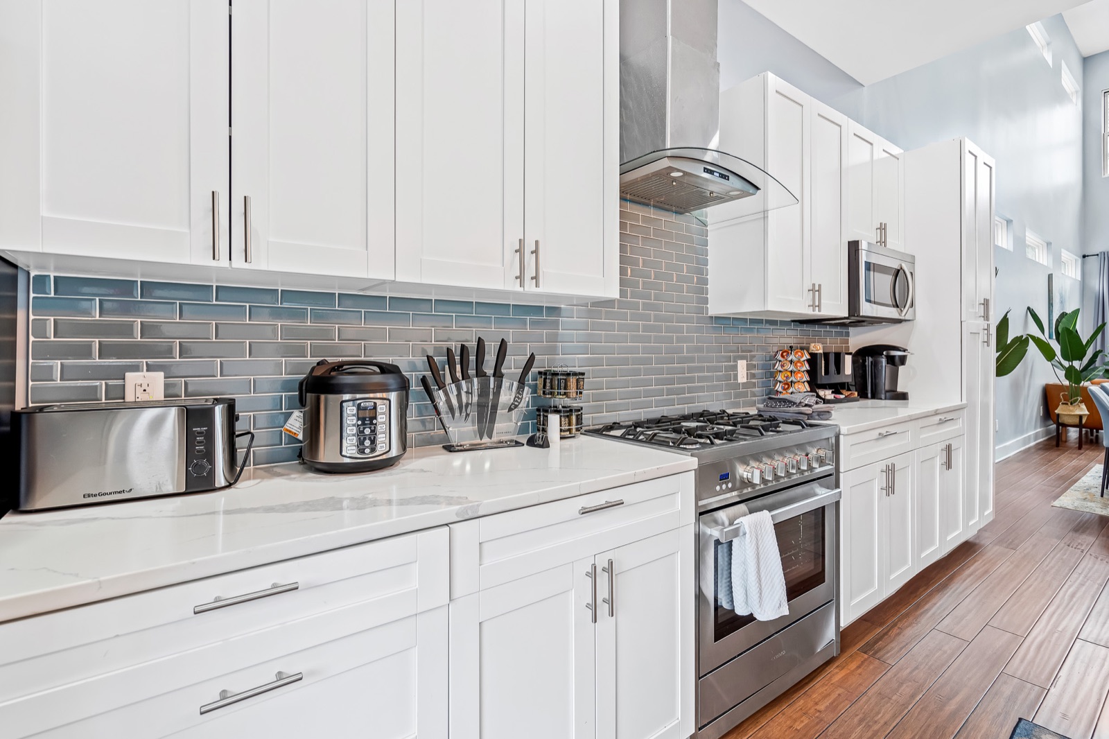 White shaker kitchen with quartz counters and blue glass backsplash